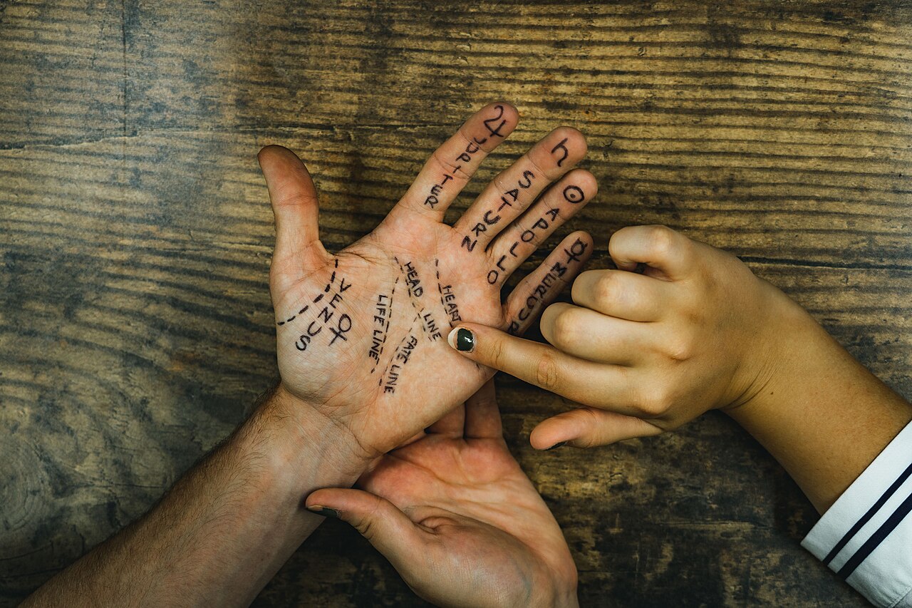 A palm reader pointing to the major lines on an open hand